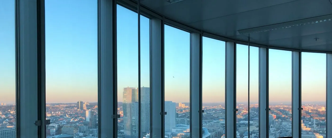 A meeting room high in an office tower looking out over a city at dusk