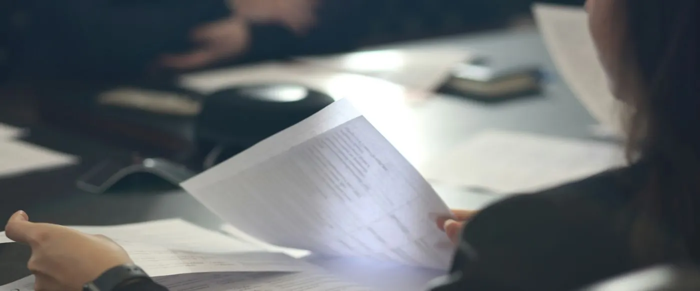 A woman reading through a printed document at a meeting table
