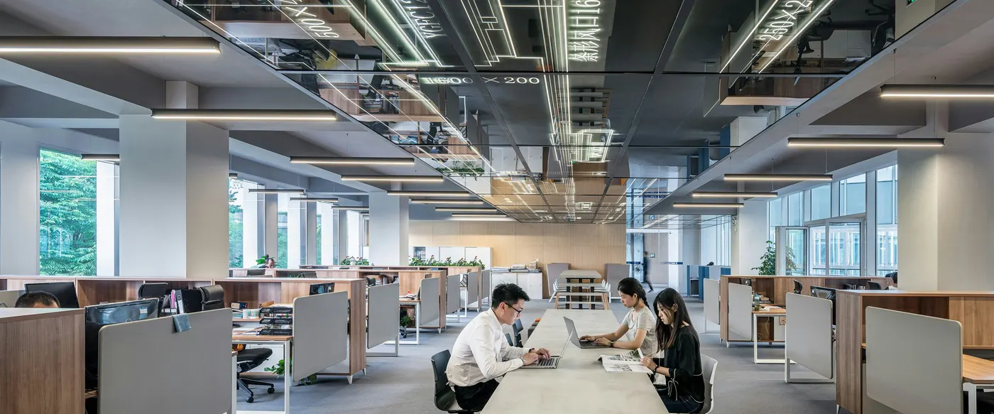 Colleagues working at a shared table in a large open-plan office