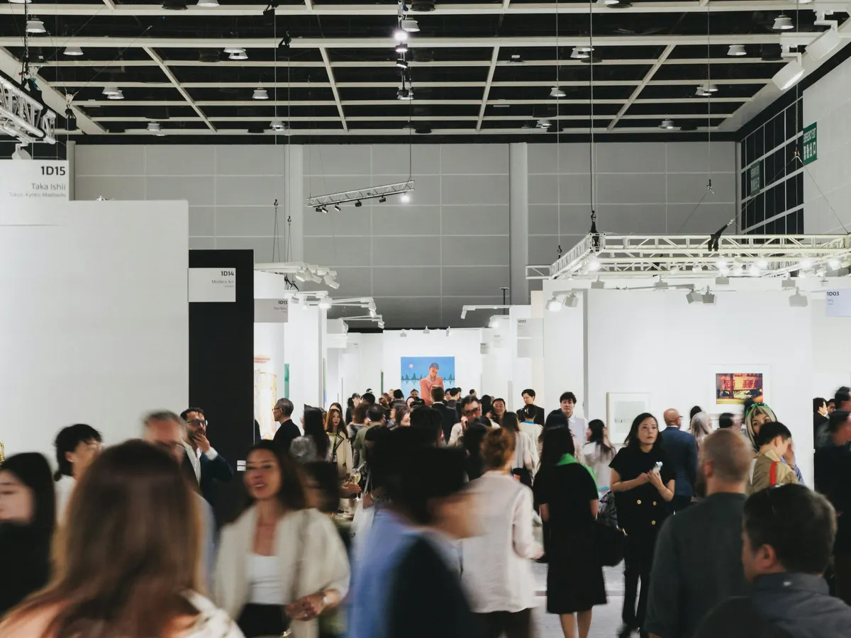 Visitors walking between white exhibition stands in a busy hall