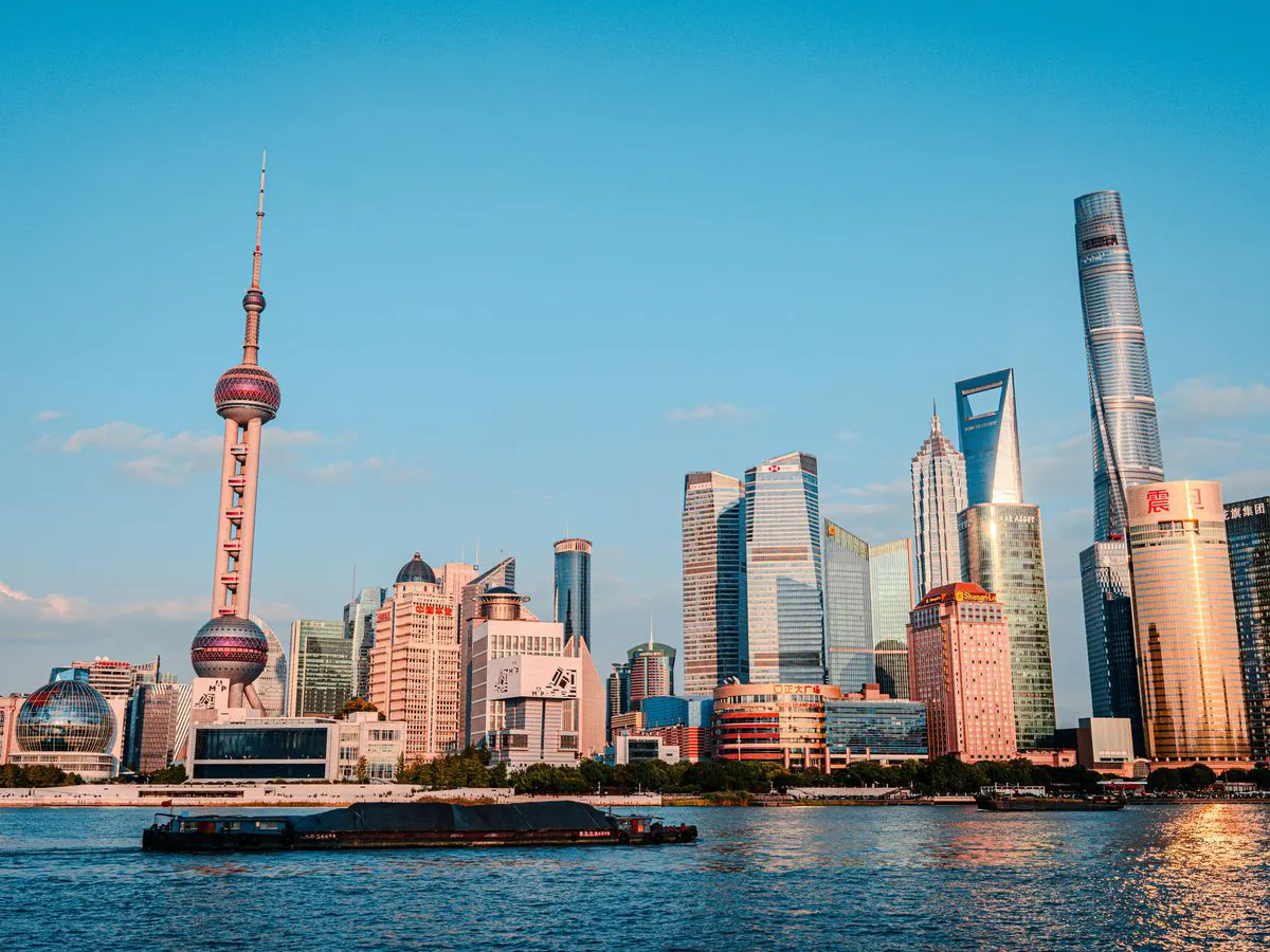 The Lujiazui skyline in Shanghai across the Huangpu River, with the Oriental Pearl Tower and Shanghai Tower, on a clear evening