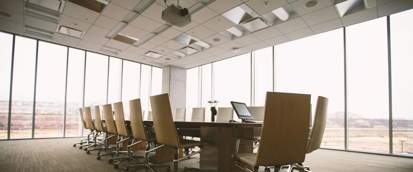 An empty boardroom with a long table and a wall of windows