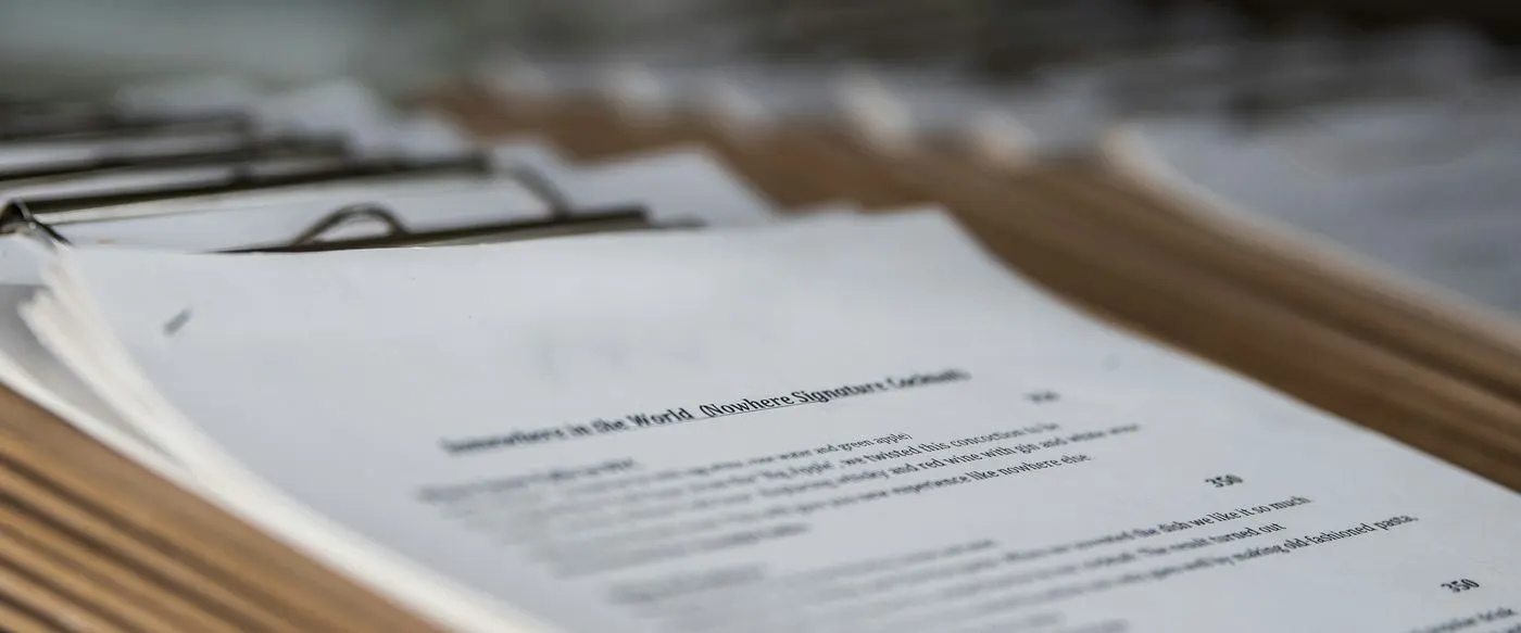 Printed documents clipped to boards and stacked on a table
