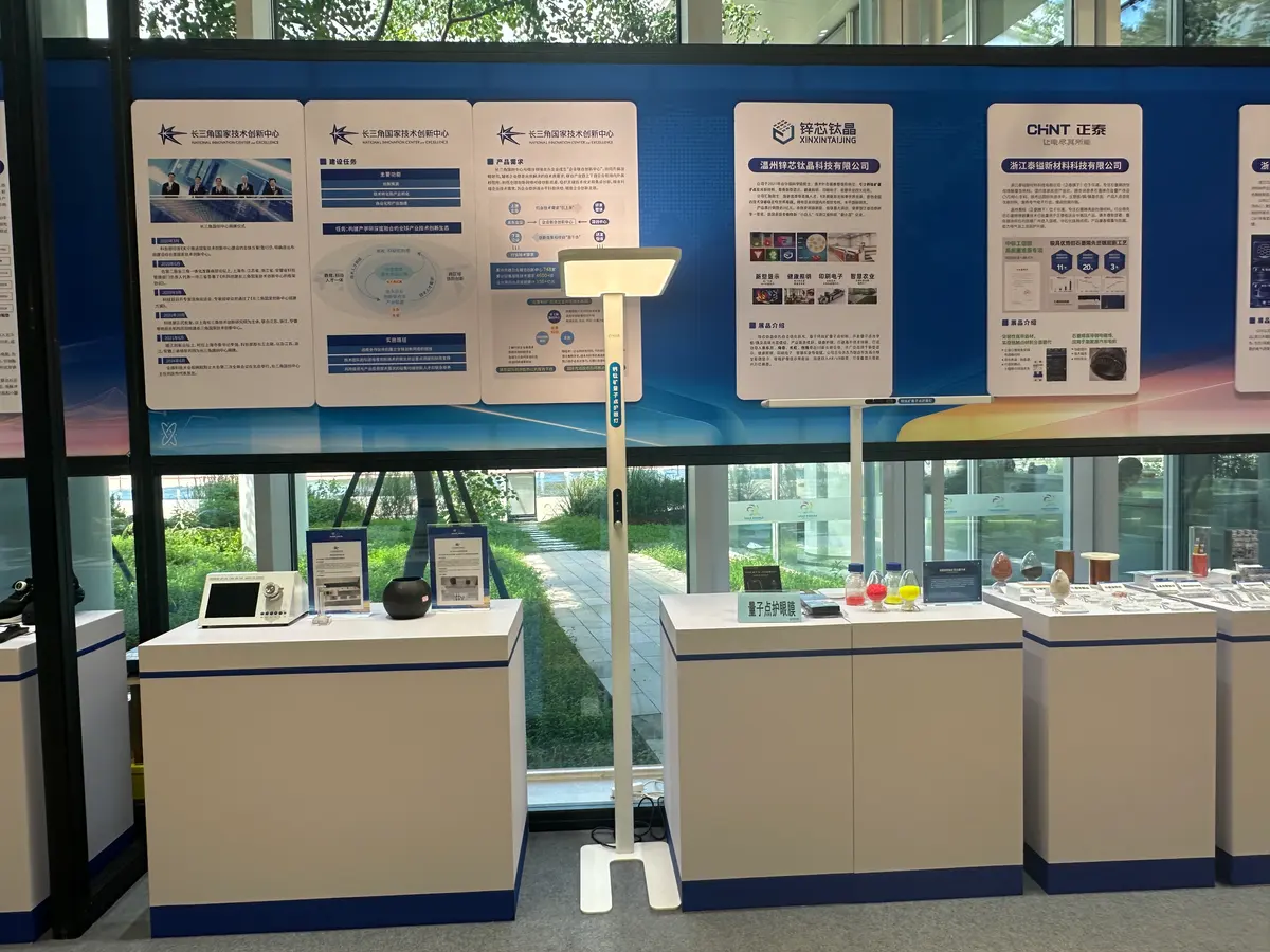 Exhibition panels for CHINT’s new-materials company and other materials makers, with product samples and a floor lamp on white plinths