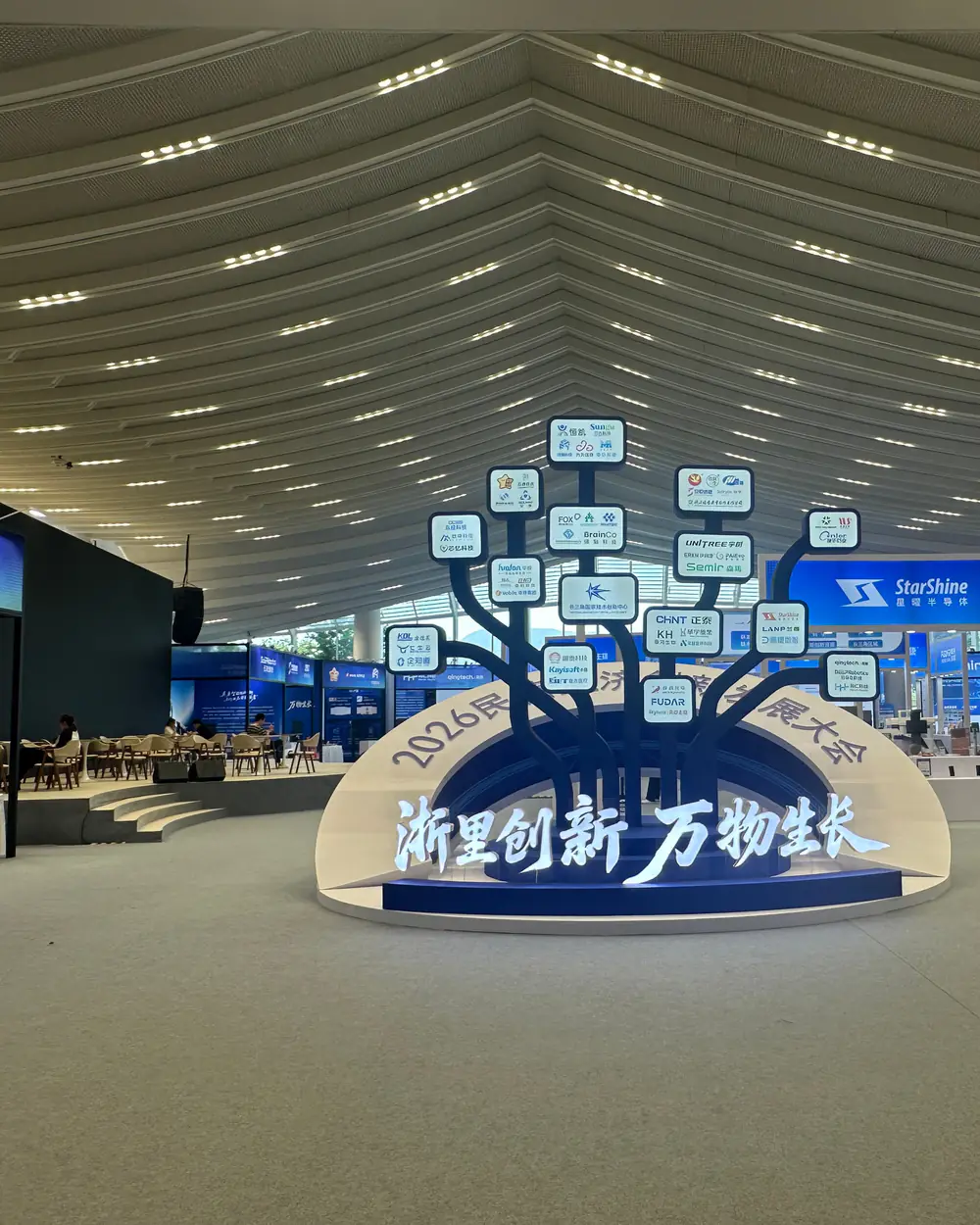 Exhibition hall at Wenzhou Garden Expo Park with a tree-shaped installation carrying exhibitor logos above the title 浙里创新 万物生长